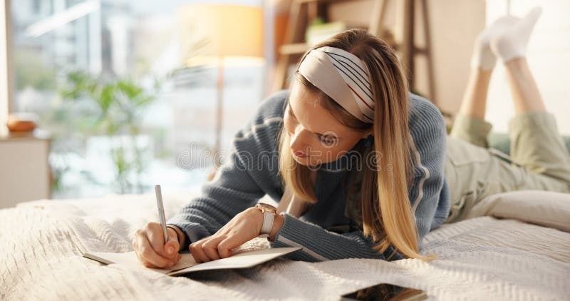 Kvinna skriver i ett block på sängen inför sina studier